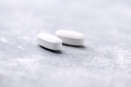 White pills on a gray background. Focus on foreground, soft bokeh.