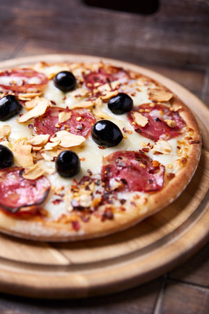 pizza with salami, olives and cheese on wooden background