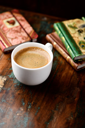 Cup of coffee with books on old wooden table, selective focusの写真素材
