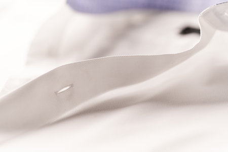 Close up of a white shirt with a purple ribbon on it.