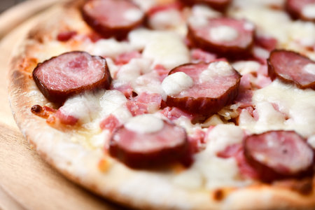 Pizza with ham and mozzarella cheese on a wooden boardの写真素材