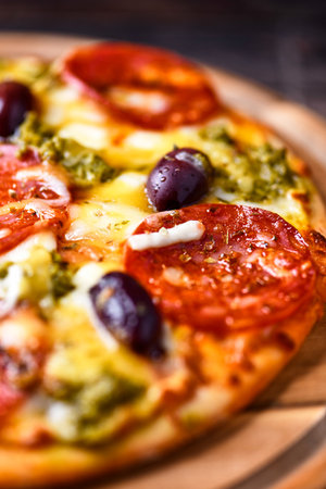 Pizza with mozzarella cheese, olives and tomato on wooden backgroundの写真素材