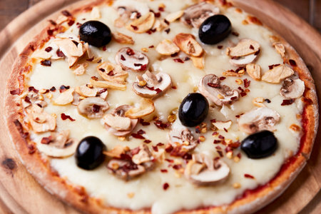 Pizza with mushrooms, olives and cheese on a wooden backgroundの写真素材