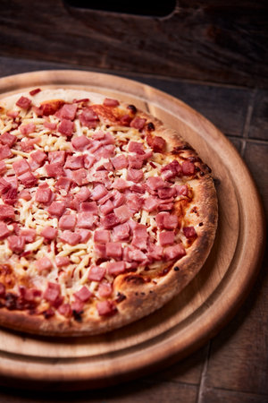Pizza with ham and cheese on a wooden board. Selective focus.の写真素材