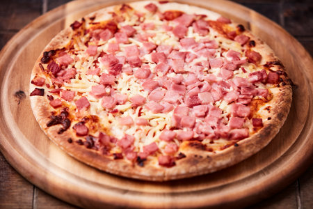 Pizza with ham and cheese on a wooden background. Toned.の写真素材