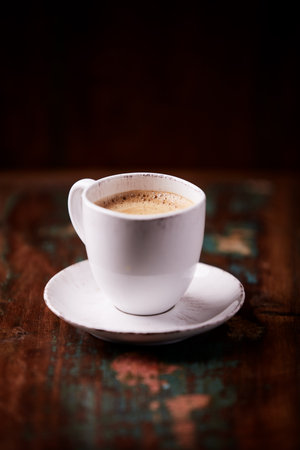 Cup of coffee on old wooden table. Shallow doof.の写真素材