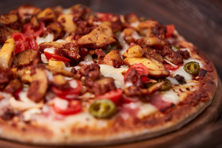 Pizza with sausages, cheese and vegetables on a wooden backgroundの写真素材
