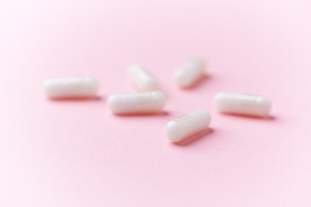 Close up of white pills on pink background with copy space.