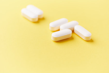 White pills on yellow background. Focus on foreground, soft bokeh.