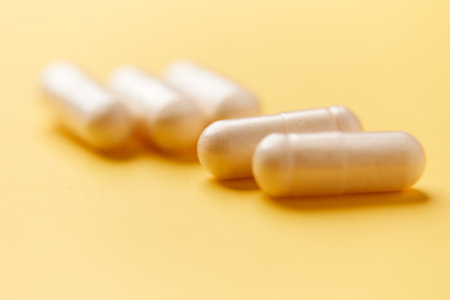 White capsules on yellow background. Focus on foreground, soft bokeh.