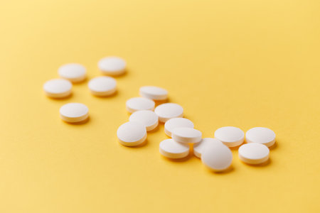 White pills on yellow background. Focus on foreground, shallow DOF.