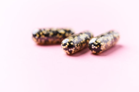 Close up of three capsules isolated on pink background with copy space.