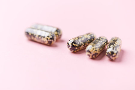Vitamin C capsules on pink background. Copy space for text.