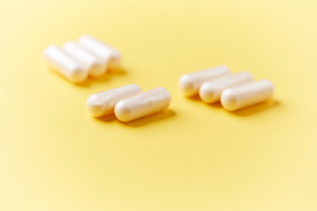 Group of white capsules on yellow background. Focus on foreground, soft bokeh.