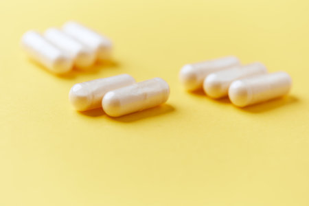 Close up of white pills on yellow background. Focus on foreground, soft bokeh. Pharmacy drug store...