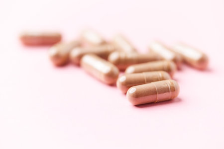 Pills isolated on pink background. Close up. Focus on foreground.
