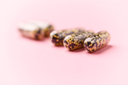 Close up of pills on pink background. Focus on foreground, soft bokeh.