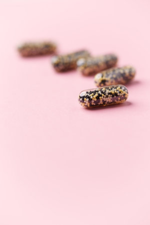Capsules with poppy seeds on a pink background. Selective focus.