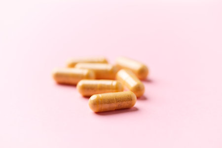 Capsules of pills on pink background. Close up.