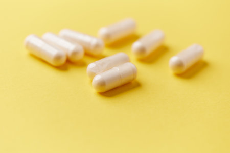 White pills on yellow background. Focus on foreground, soft bokeh.