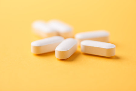 White pills on yellow background. Focus on foreground, soft bokeh.