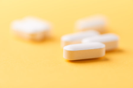 Close up of white pills on yellow background. Focus on foreground, soft bokeh. Pharmacy drug store concept.の写真素材