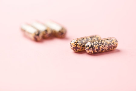 Close up of two pill capsules on pink background with copy space.