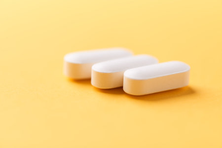 White pills on yellow background. Focus on foreground, soft bokeh.の写真素材
