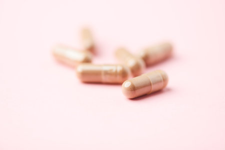Close up of pills on pink background. Focus on foreground, soft bokeh. Pharmacy drug store concept.
