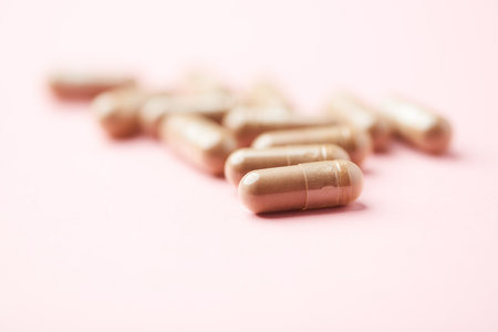 Close up of capsule pills on pink background. Focus on foreground.の写真素材