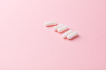White pills on pink background. Copy space for text. Focus on foreground.