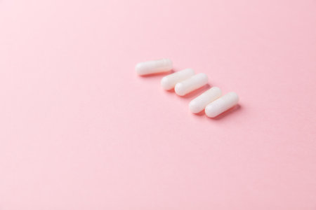 White pills on pink background, closeup. Concept of healthy lifestyle