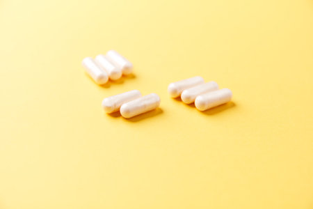 White pills on yellow background. Focus on foreground, soft bokeh.