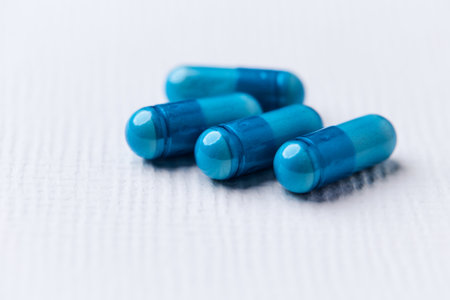 Blue pills on a white background. Focus on foreground, shallow depth of field.の写真素材