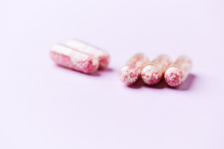 Pink pills on a purple background. Focus on foreground, soft bokeh.