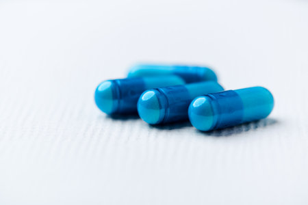 Blue pills on a white background. Focus on foreground, soft bokeh.の写真素材