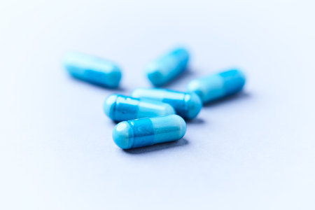 Blue pills on a white background. Focus on foreground, soft bokeh.