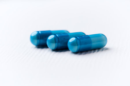 Blue pills on a white background. Focus on foreground, soft bokeh.