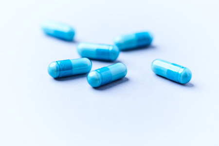 Blue pills on a white background. Focus on foreground, soft bokeh.