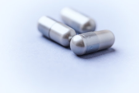 Close-up of silver pills on white background. Focus on foreground.