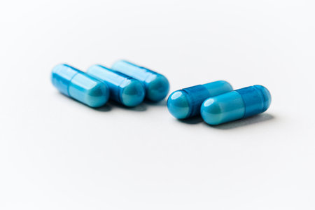 Blue pills on white background. Focus on foreground, soft bokeh.の写真素材