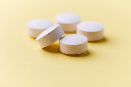 White pills on yellow background. Focus on foreground, soft bokeh.の写真素材
