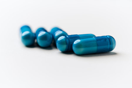 Blue pills isolated on a white background. Focus on foreground, soft bokeh.