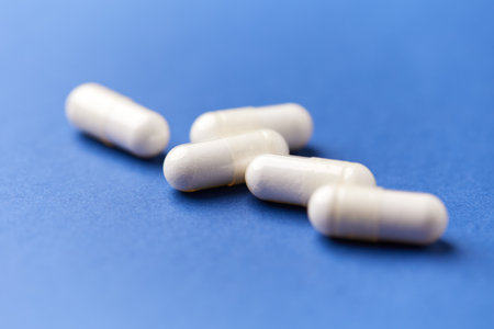 White pills on blue background. Focus on foreground, soft bokeh.