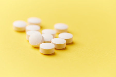 White pills on yellow background. Focus on foreground, soft bokeh.