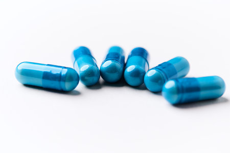 Blue pills isolated on white background. Focus on foreground, soft bokeh.