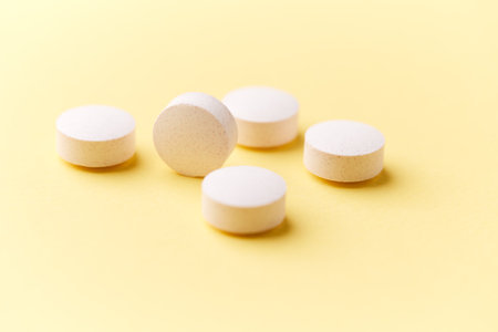 White pills on yellow background. Focus on foreground, soft bokeh.