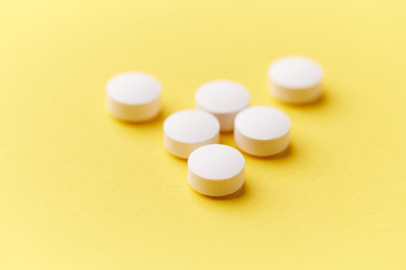 White pills on yellow background. Focus on foreground, soft bokeh.