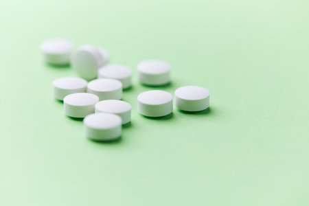White pills on green background. Focus on foreground, soft bokeh.の写真素材