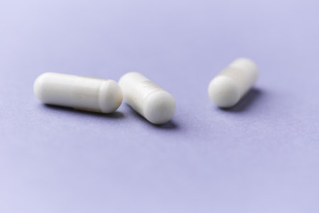 White pills on a purple background. Focus on foreground, soft bokeh.